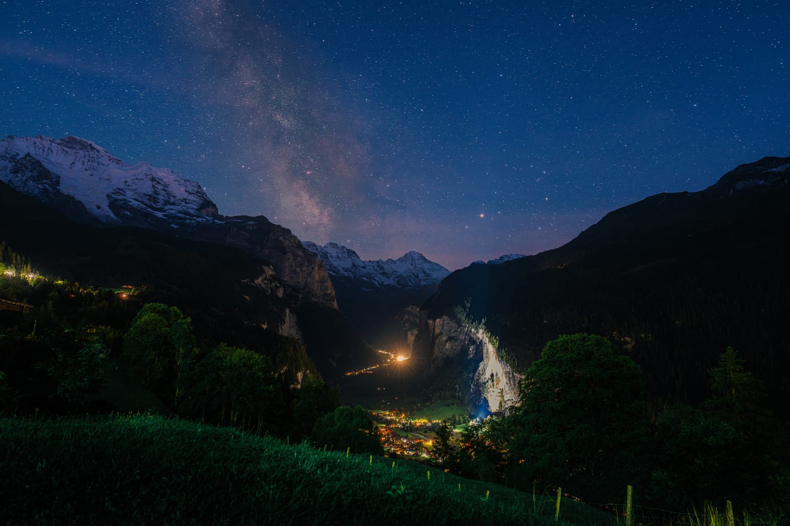 Milky Way over a valley with village lights.