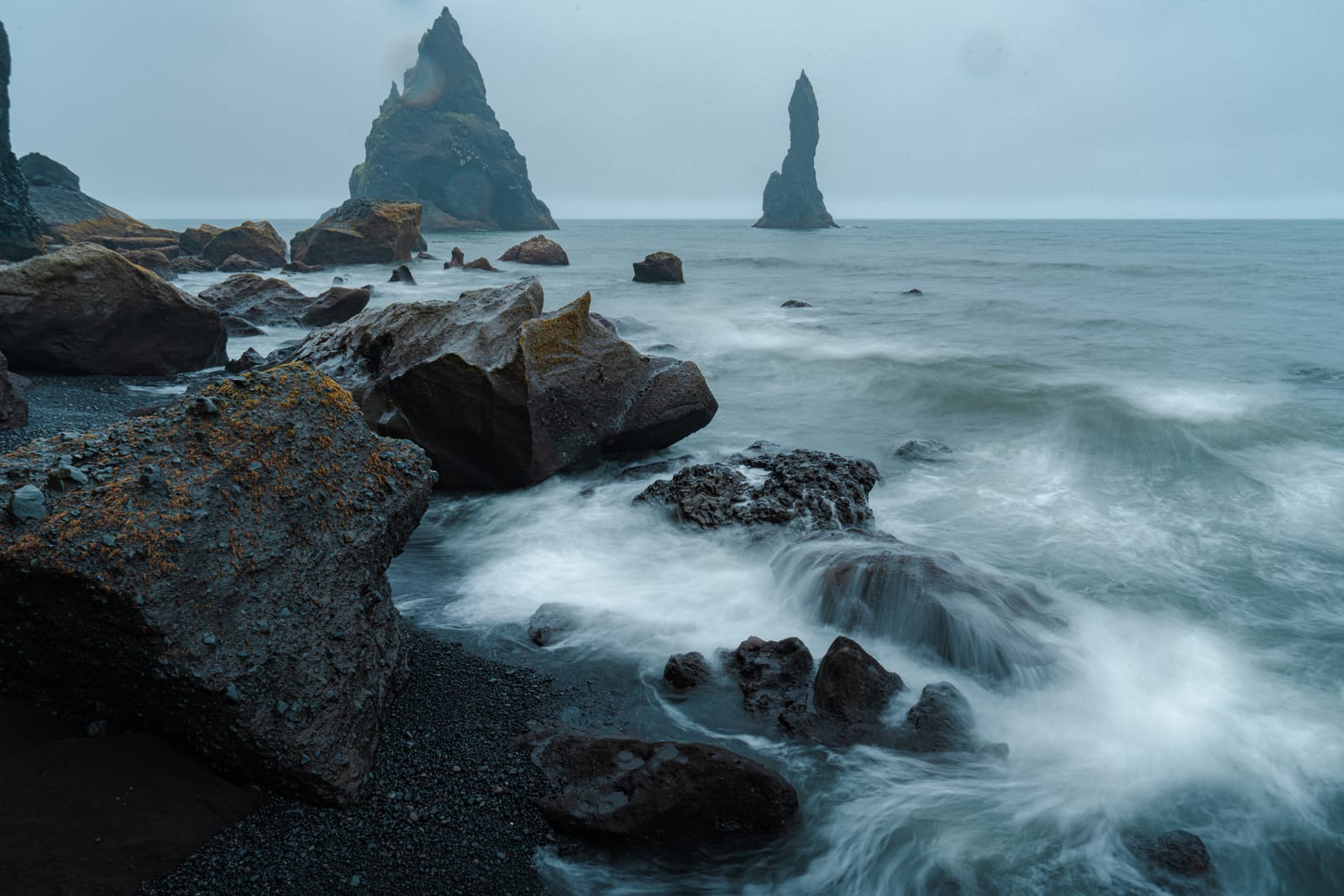 Sea stacks with long-exposure surf, black sand.