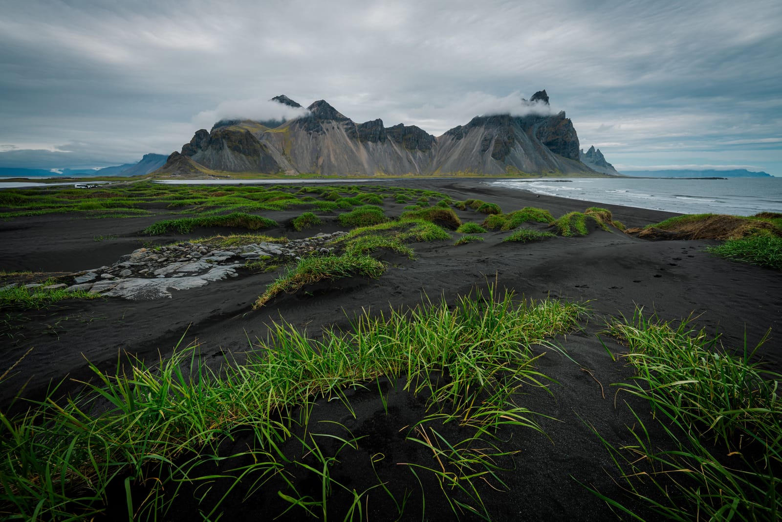 Coastal mountain over black dunes and grass.
